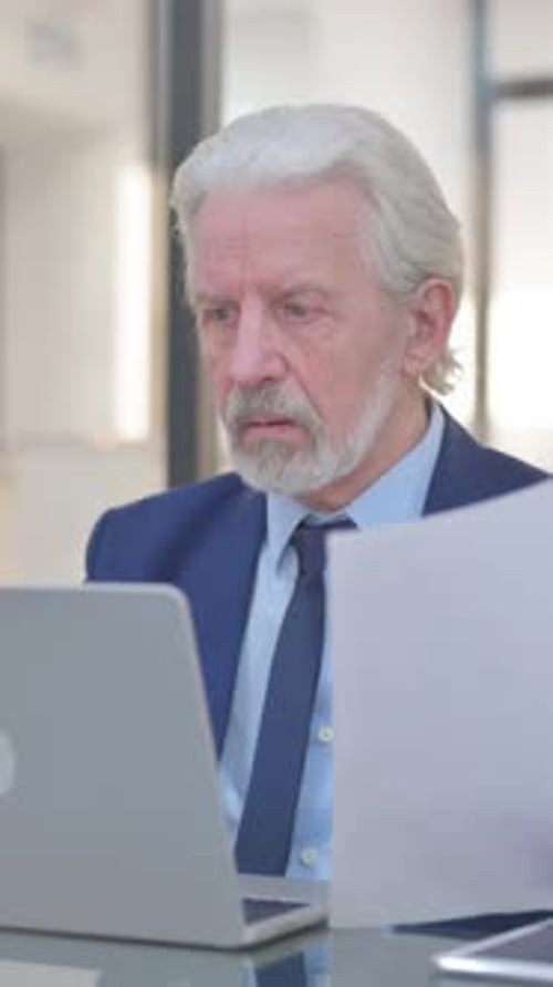 Senior Businessman Works at Desk with Laptop Indoors