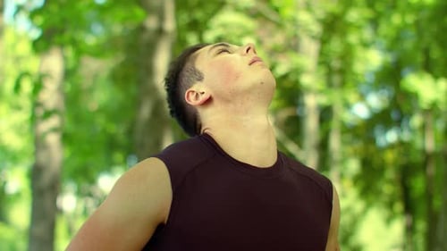 Young Man Stretching Neck in Park Setting