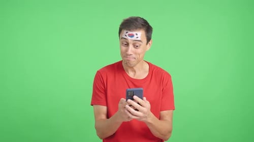 South Korea Supporter Looking at His Mobile Smiling and Showing It