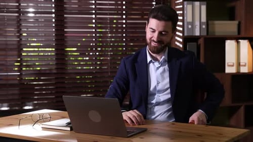 Hübscher Geschäftsmann arbeitet am Laptop am Holzschreibtisch im Büro