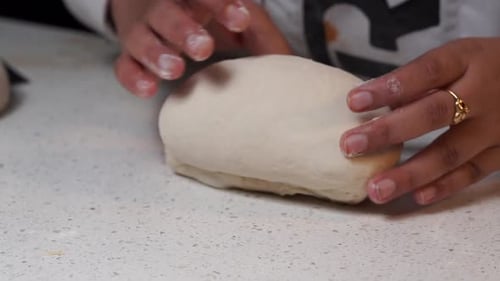 Hands Kneading Dough on Kitchen Countertop