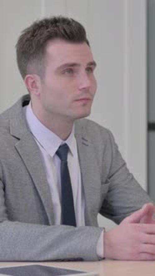 Jovem empresário pensativo pensando enquanto está sentado no trabalho, vídeo vertical