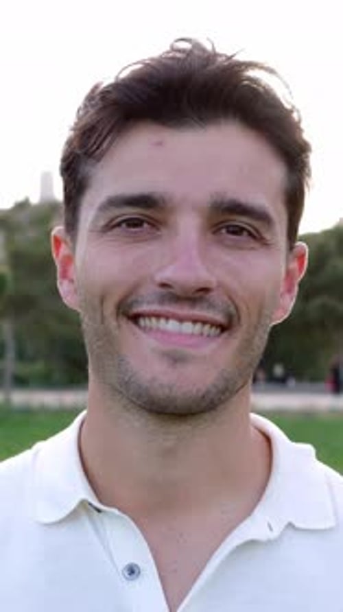 Outside Portrait of Young Smiling Handsome Man Looking at Camera at City Park