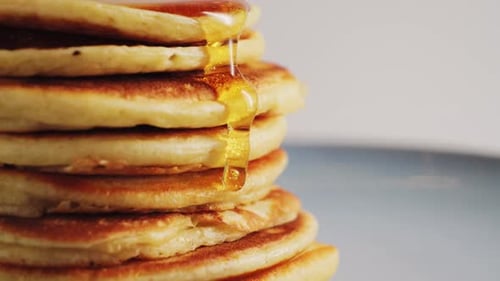 Close Up Pouring Honey Over Stack of Pancakes Concept of Sweet Brunch