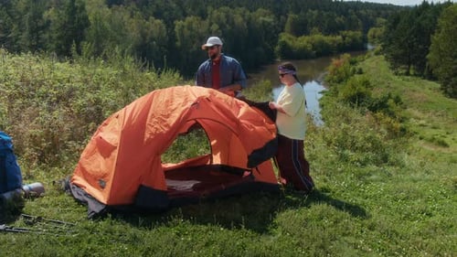 Man and Woman with Down Syndrome Setting Up Tent While Hiking in Lush Forest