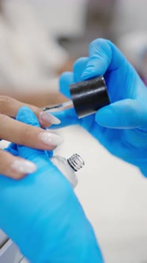 Close Up Of Beautician Hands Applying Nail Polish On Client's Fingernails In Beauty Salon