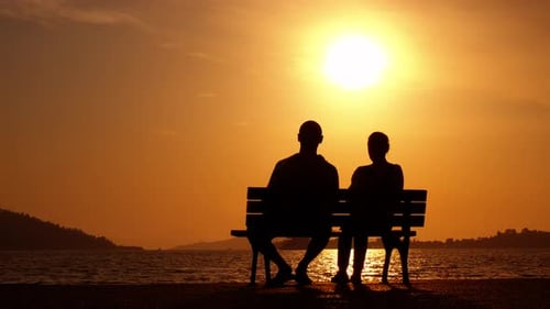 Couple enjoy sea coast on bench.