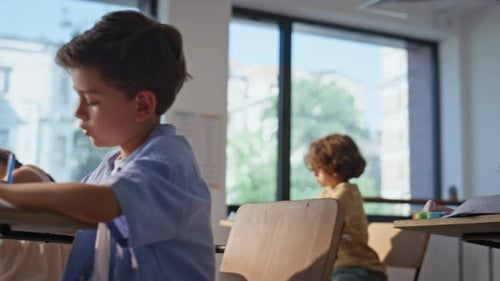 Elementary School Pupils Writing in Copybooks Sitting Desks Group Classmates