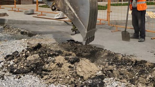 Bucket of the Excavator Breaks the Old Asphalt