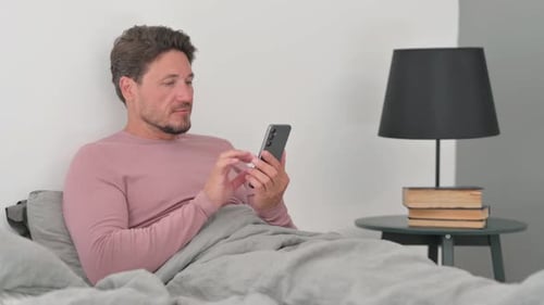 Man in Bed Using Smartphone Device