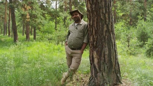 Portrait of Biracial Male Forest Warden Leaning on Tree