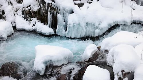 River Stream at Winter Snow Forest in the Mountains