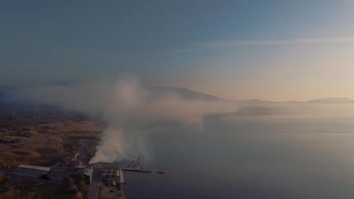 Aerial Over Factory On Lesbos Coastline Next To Aegean Sea Pumping Out Smoke From Chimney. Follow Sh