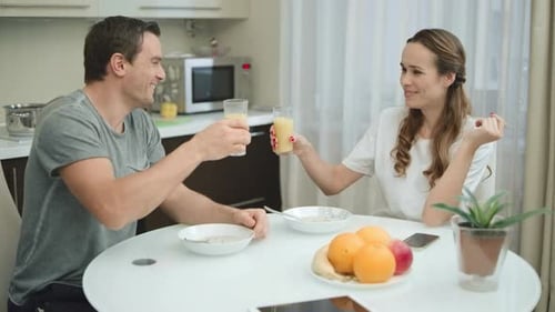Couple Sharing Breakfast and Toasting Juice in Kitchen