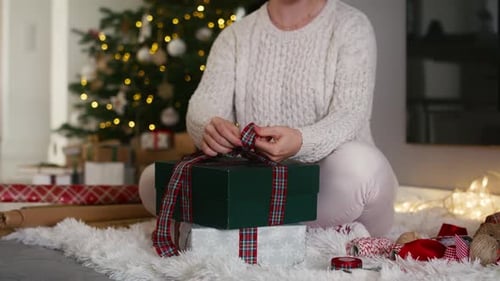 Woman Tying Ribbon on Christmas Gift