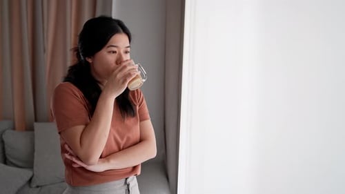 Mujer asiática de pie y bebiendo agua