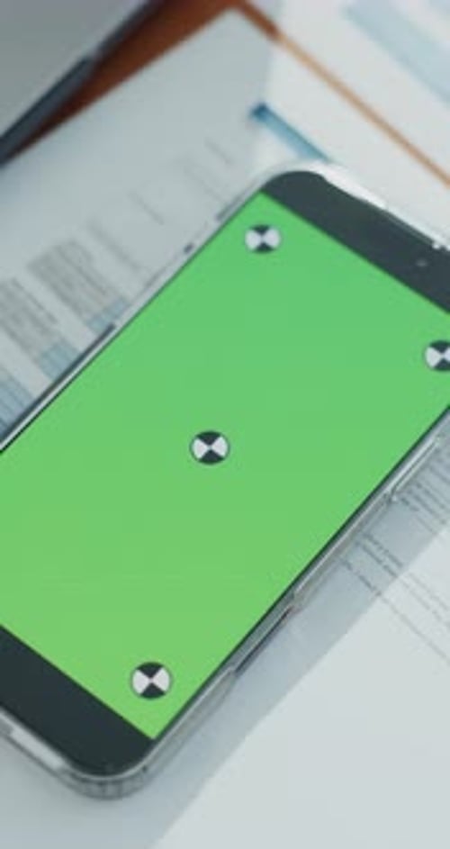 Phone, green screen and documents at empty office, admin and mockup space for advertising at finance