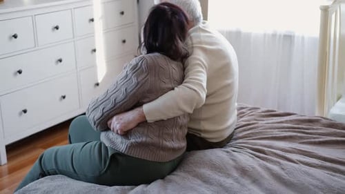 Senior Couple Embracing Tenderly on Bed at Home