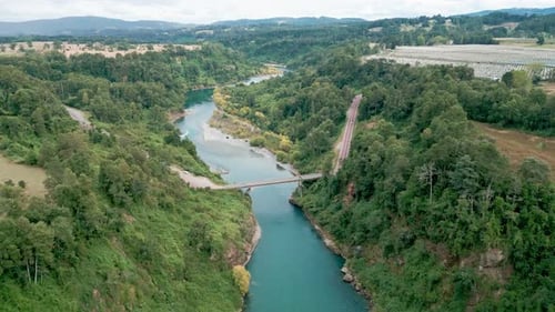 Forward flight over turquoise river with bridge and forest. Malihue, Los Lagos, Chile