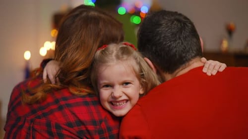 Loving Family Embraces in Front of Christmas Tree
