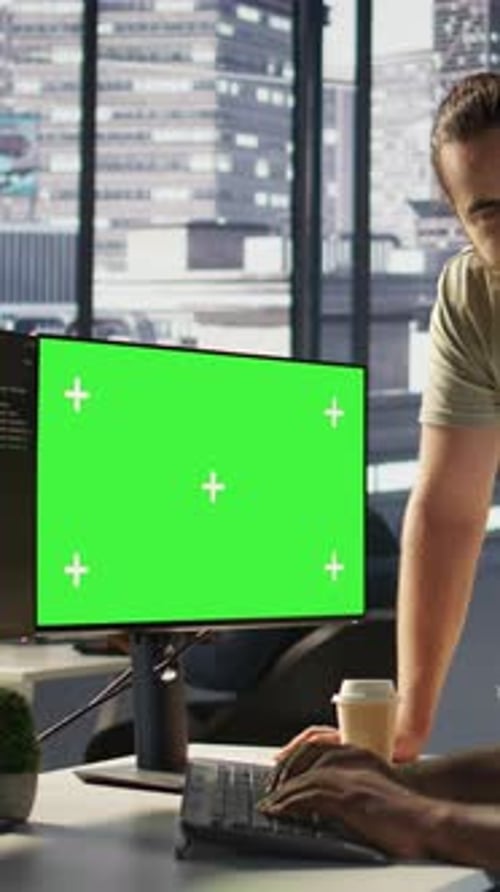 Vertikaler Videoadministrator beim Software-Debugging auf einem Greenscreen-PC mit einem Kollegen