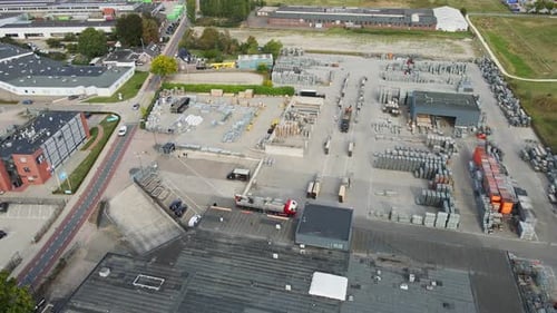 Drone flying over the rooftop of a large company building and revealing a organized storage yard