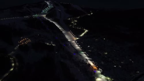 Flying Over Ski Slope and Ropeway with Gondolas at Ski Resort at Night