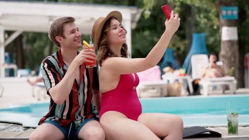 Couple Enjoying By Pool Taking a Selfie Sipping Tropical Drinks Creating Happy Memories