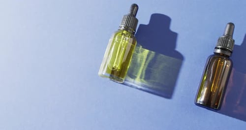 Close up of dropper serum bottles on blue background with copy space