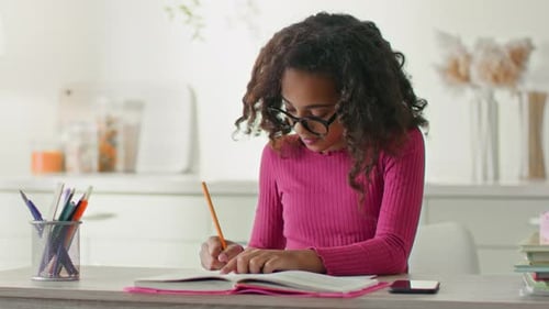 Teen Girl Studies with Pencil at Kitchen Table