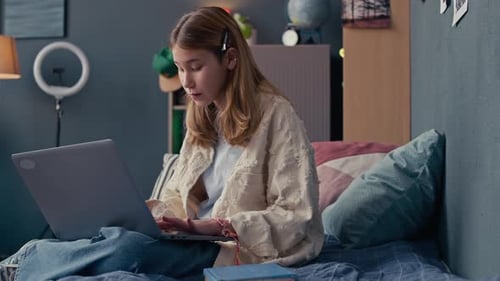 Teen girl using laptop in bedroom at home
