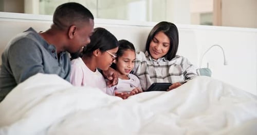 Family Relaxing in Bed with Tablet
