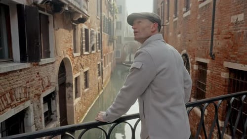 Man Admiring Historic Canals Of Venice From A Bridge
