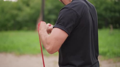 Man Exercising with Resistance Band in Outdoor Gym