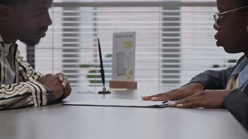 Man Signing Contract with Bank Consultant Giving Passport in Office