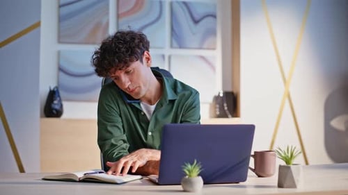 Man Talking on Phone while Working at Laptop