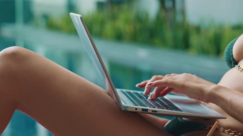 Young Blogger in Bikini Types on Laptop Resting on Poolside Close Up
