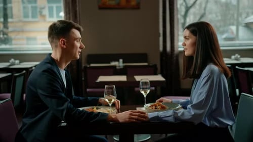 Date in the hotel restaurant dinner man and woman drink white wine in glasses and taste food