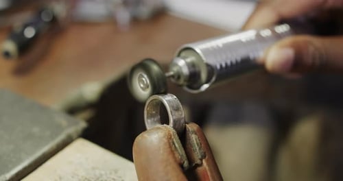 Biracial female worker shaping ring using handcraft tools in workshop in slow motion