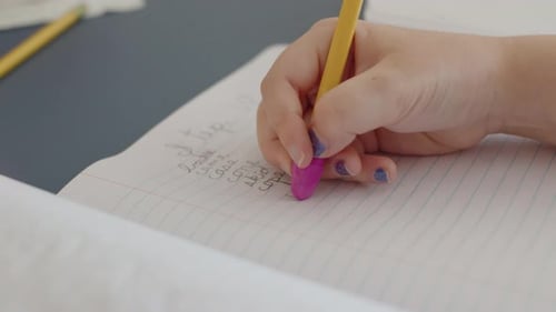 Child Writes in Notebook, Erases Mistake