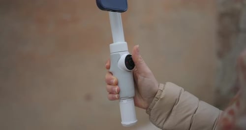 View Of Person Pressing Button On Insta360 Flow Gimbal To Turn Attached Mobile Into Landscape Mode.