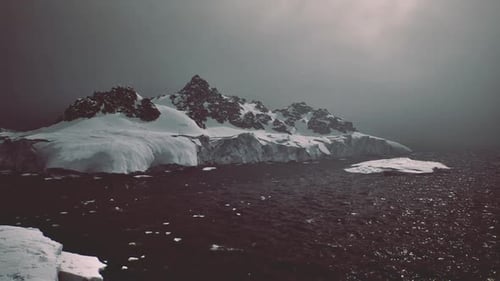 Antarctic Snowy Mountains and Icebergs Under Dark Sky