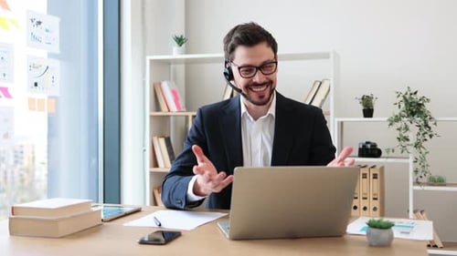 Business Professional Using Laptop Headset for Online Communication in Office