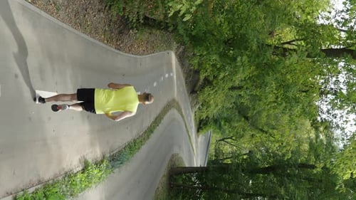Vertical Screen Man Jogging on Empty Road Between Trees