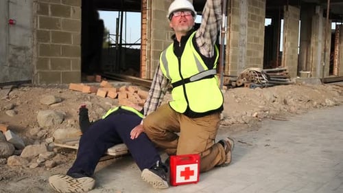 Worker calling help trying to revive an unconscious colleague after an accident at construction site