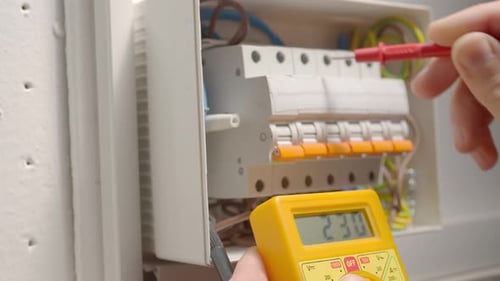 Work Under Voltage Electrician is Checking Serviceability of Equipment Measuring Voltage By Yellow