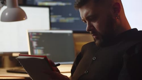 Programmer Taking Notes in the Office Selective Focus of Bearded Man Writing in the Notebook at His