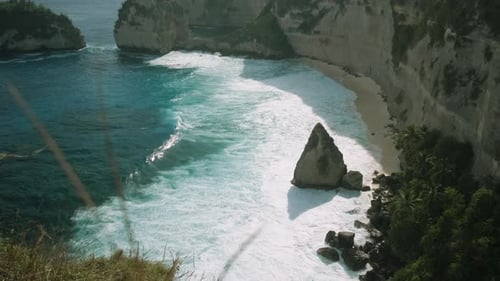 Rock in the ocean with beautiful palms behind at Atuh beach on Nusa Penida island, Indonesia
