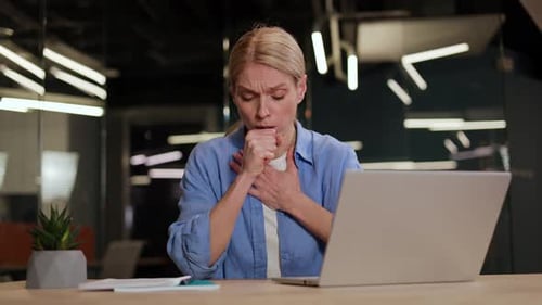 Woman Coughing at Desk in Office Setting