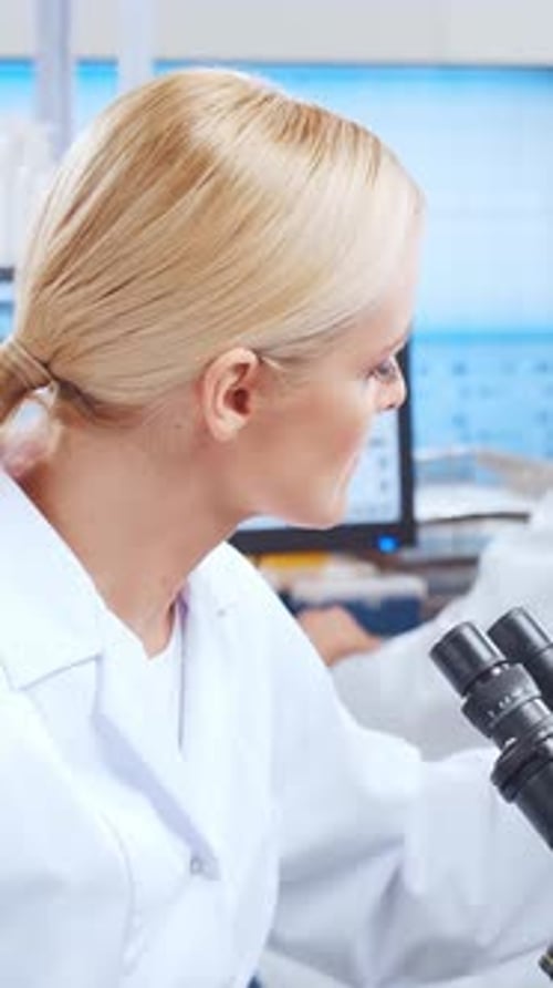 Woman Scientist Looks Through Microscope in Laboratory Setting